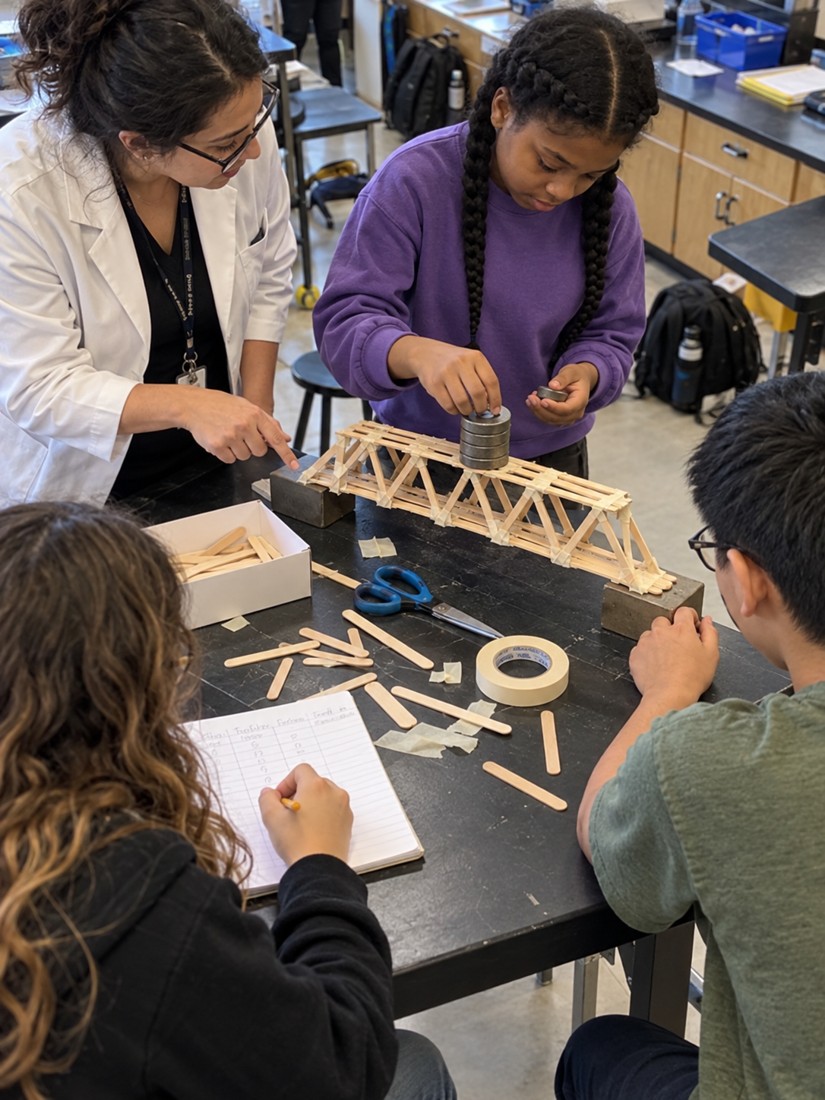 Middle school students testing a craft-stick bridge